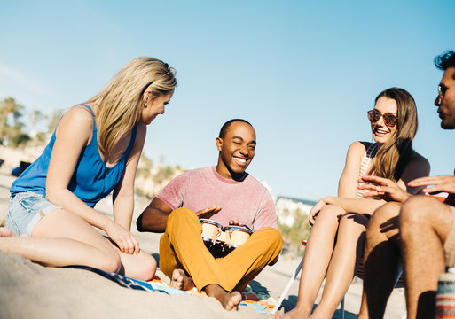 Man with friends bongo drumming on beach, Santa Monica, California, USA