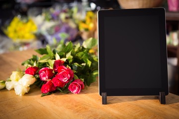 Obraz premium Bunch of roses and digital tablet on the wooden table