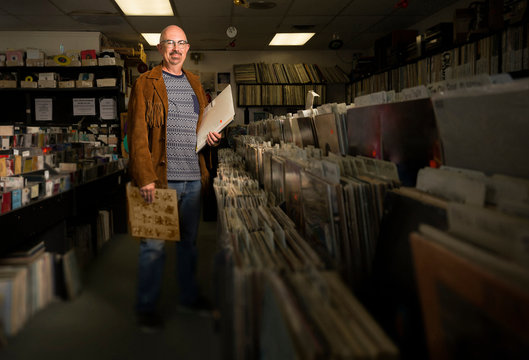 Portrait of mature man in record shop, holding records
