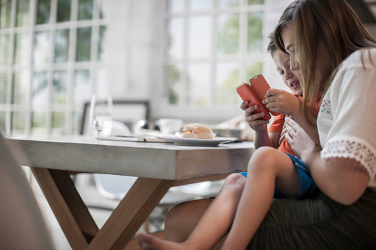 Mother and son using smartphone at dining table
