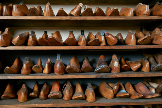 Rows of old wooden shoe lasts on shelves in traditional shoe shop, front view