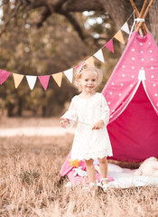 Happy kid girl 2-3 year old playing over wigwam outdoors