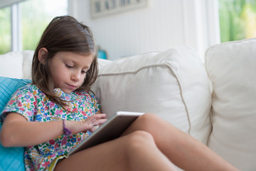 Girl on sofa using digital tablet