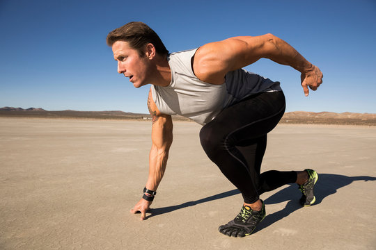 Male runner on his marks on dry lake bed, El Mirage, California, USA