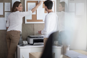Female designer pinning plans on notice board in design studio