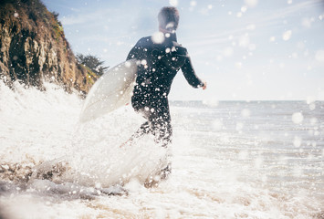 Surfer running into sea, Santa Barbara, California, USA