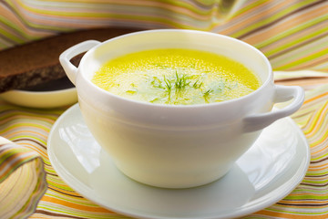 Clear soup with dill in a white bowl