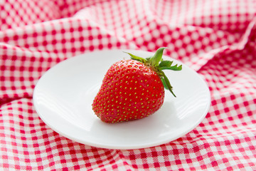 Fresh organic strawberry in white plate on red napkin