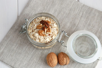 Oat flakes and walnuts in a glass jar on the table