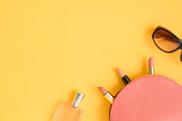 Top view of cosmetic bags with lipsticks, glasses, perfume