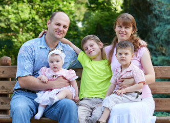 happy family portrait on outdoor, group of five people sit on wooden bench in city park, summer season, child and parent