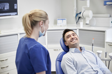 Obraz premium happy female dentist with man patient at clinic