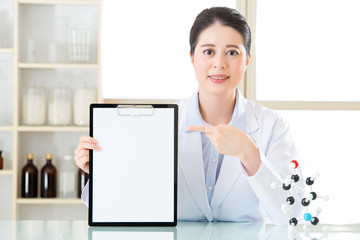 Happy asian female scientist showing blank clipboard and point i