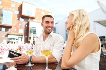 happy couple with wallet paying bill at restaurant