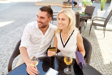happy couple with wallet paying bill at restaurant