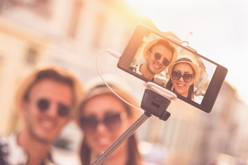 Beautiful young tourist couple taking picture of themselves with selfie stick - Sunset, Golden...