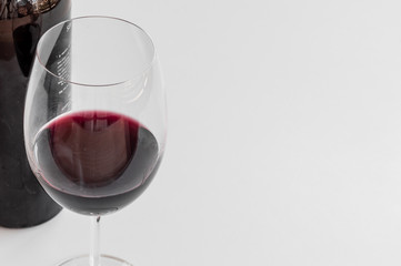 Close up of glass and bottle of red wine on white background. Copy space.