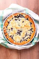 Top view on blueberry pie in a baking dish with a towel around