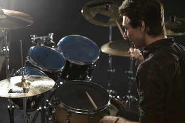 Fototapeta na wymiar Rear View Of Drummer Playing Drum Kit In Studio
