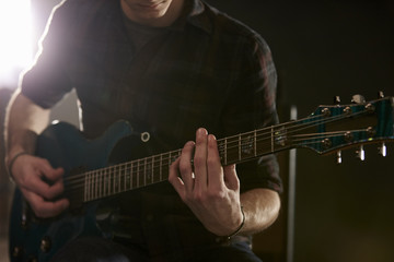 Close Up Of Man Playing Electric Guitar In Studio