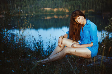 Girl sitting by the lake with bare feet