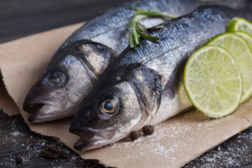 Raw seabass fish on the wooden board with vegetables