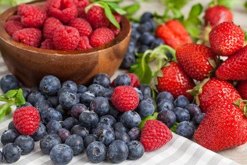 fresh raspberries, blueberries and strawberries on wooden background