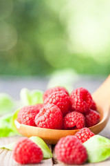 Raspberries in wooden spoon on wooden table. Natural background. Selective focus.