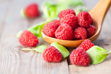 Raspberries in wooden spoon on wooden table. Natural background. Selective focus.