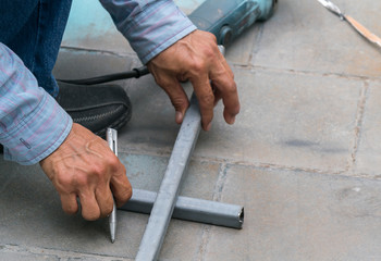 Worker measuring stainless steel railing with measuring tape in construction site
