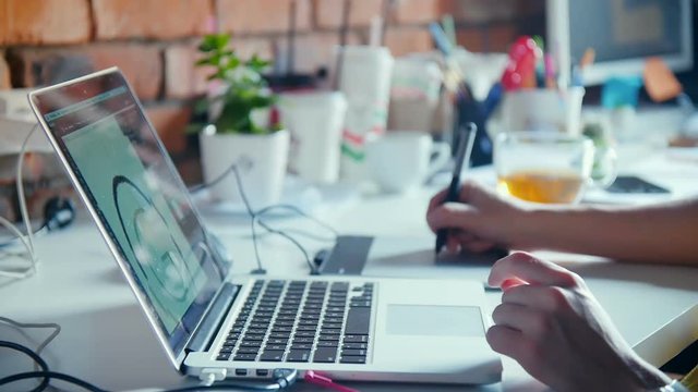 Graphic designer working with drawing tablet with pen on white surface