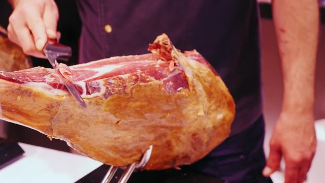 man cuts the ham into thin slices. The famous la Boqueria market in Barcelona