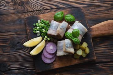 Herring rolls with onion, gherkins, lemon and basil, top view