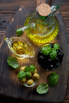 Glass bottle with olive oil, olives and green basil, close-up
