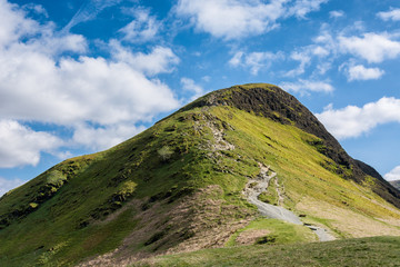 Catbells Mountain Peak with blue sky and intermittent clouds.