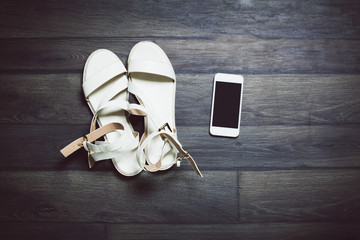 Shoes, smart phone on wooden background. Top view. Toned photo.
