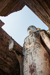 Uprisen angle view of old stand buddha statue in the ancient temple Thailand