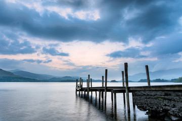 Moody dusk clouds over Derwentwater Lake with wooden jetty.