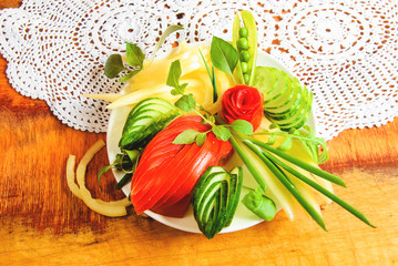 Assorted vegetables on a white plate and white laced napkin, against textured wooden background
