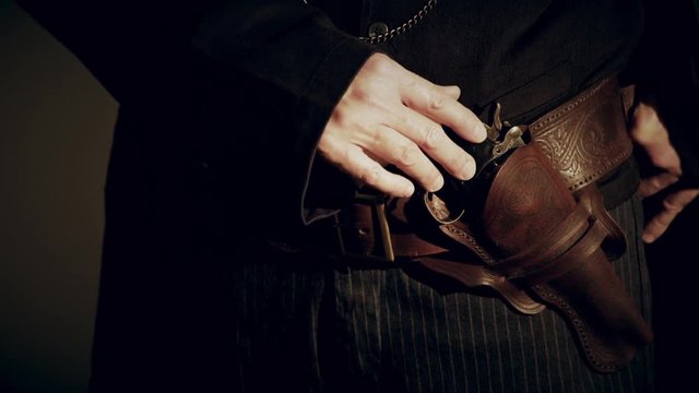 closeup of cowboy opening coat and putting hand on pistol 