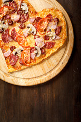 Pizza heart shape on dark wooden background top view