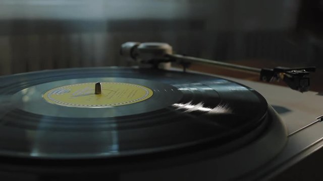 A man puts on a vinyl record and starts the gramophone close-up