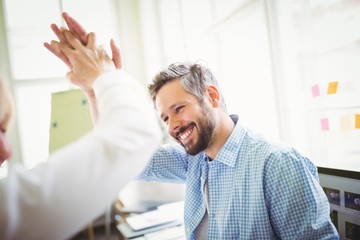 Happy coworkers giving high-five in creative office