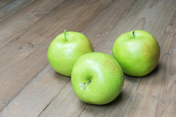 Green apples on wooden background.