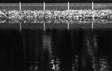 Obraz premium Horizontal black and white fence reflections on lake surface bac