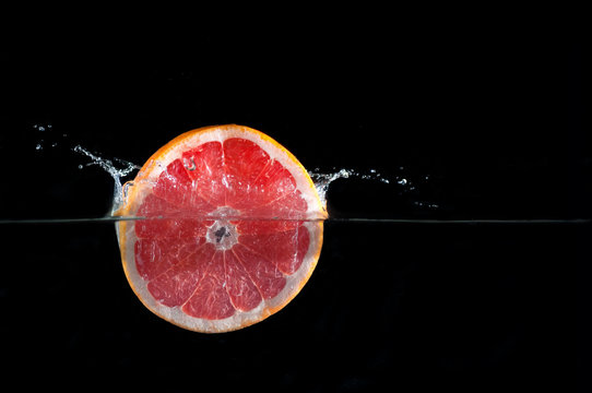 Fresh grapefruit slice dropped into water