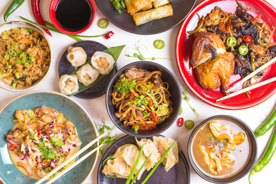 Assorted Chinese food set. Chinese noodles, fried rice, dumplings, peking duck, dim sum, spring rolls. Famous Chinese cuisine dishes on white table. Top view. Chinese restaurant concept. Asian style