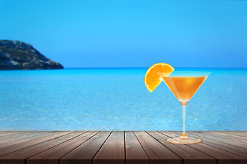 Cocktail on wooden table. In the background is the beach and the sea. Relax in the hot summer days.