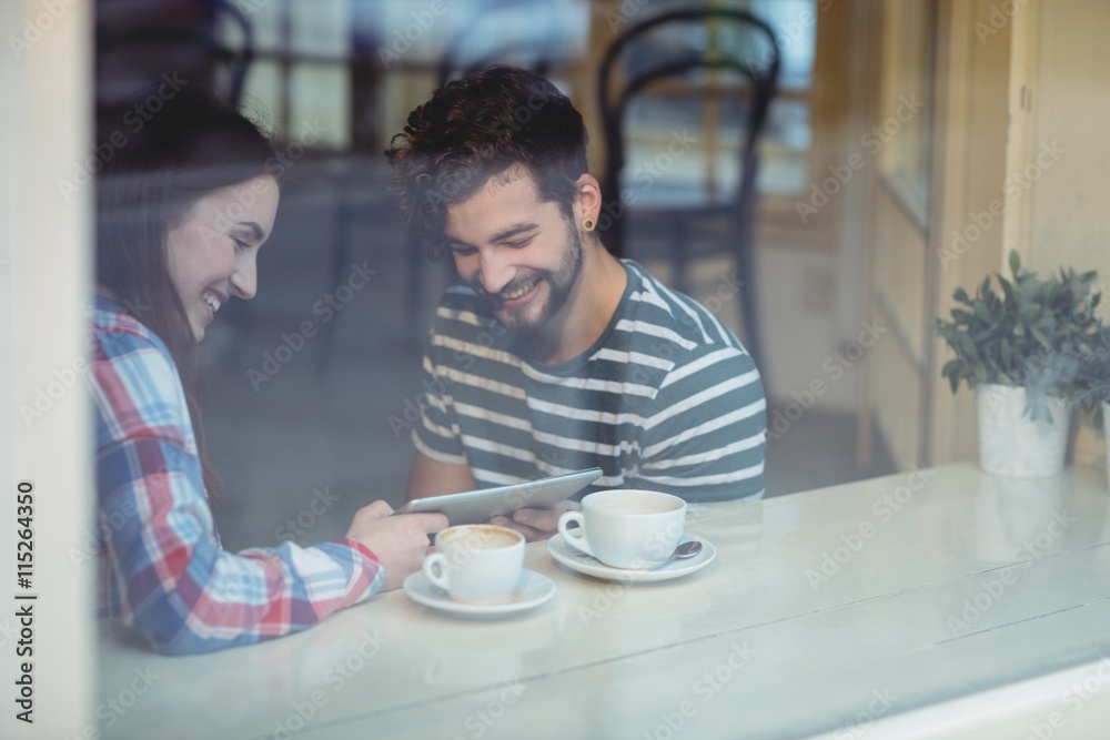 Poster couple using tablet computer at cafe