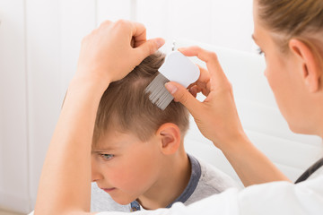 Naklejka premium Doctor Doing Treatment On Boy's Hair